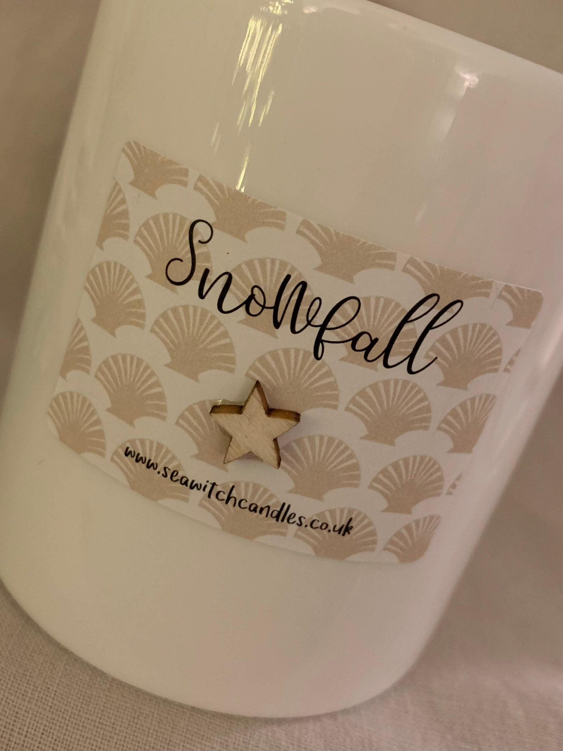 Snowfall Candle  £22  Fresh green top notes layered over warming spices on a base of musk, cedar wood and frankincense  The perfect scent for sitting by a cosy fire watching the snow fall outside  The label is hand finished with a wooden star  &nbsp;Burn time of at least 50 hours&nbsp;   Ingredients: natural vegan plant wax, fragrance oils, cotton wick  &nbsp;This candle is hand poured into a white china pot and is made in Mousehole, Cornwall by Seawitch Candles&nbsp;